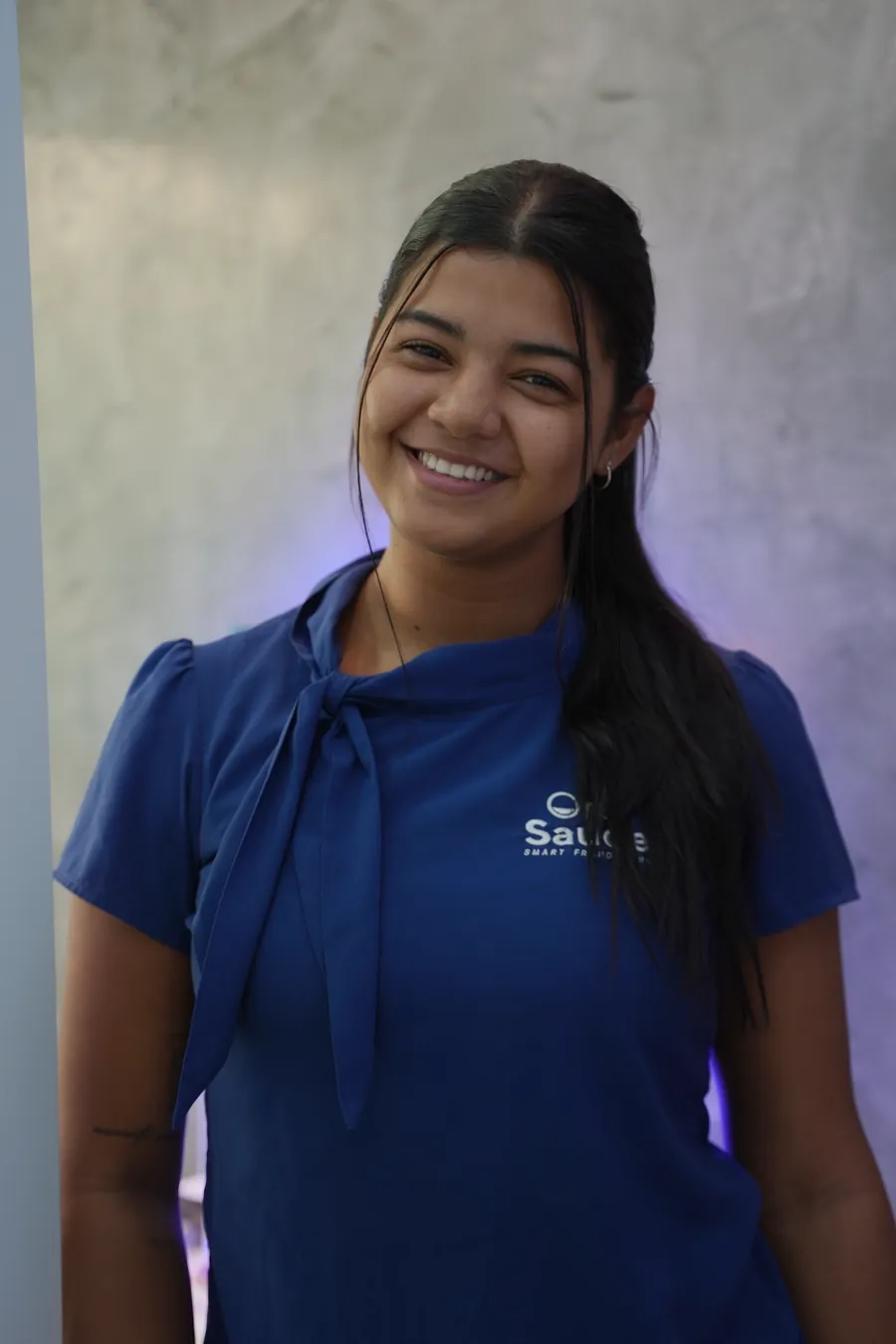 Atendente da Oral Saúde sorrindo, de uniforme azul